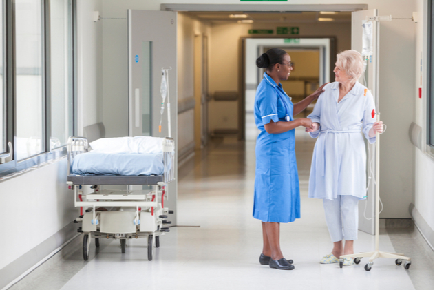 Healthcare nurse talking to patient in hallway