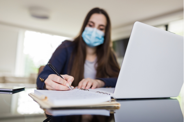 Young woman wearing medical face mask working from home.